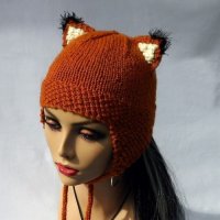 Вязаная шапка с ушками терракотового оттенка, декорированная кисточками, с завязками.